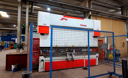 A CNC press brake behind its safety guard
