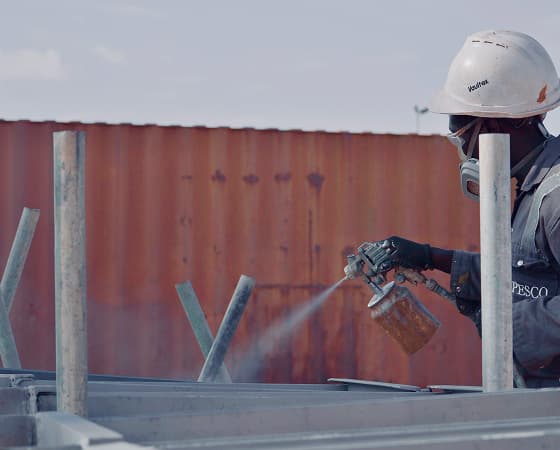 PESCO painter in a respirator spray-coating steel
