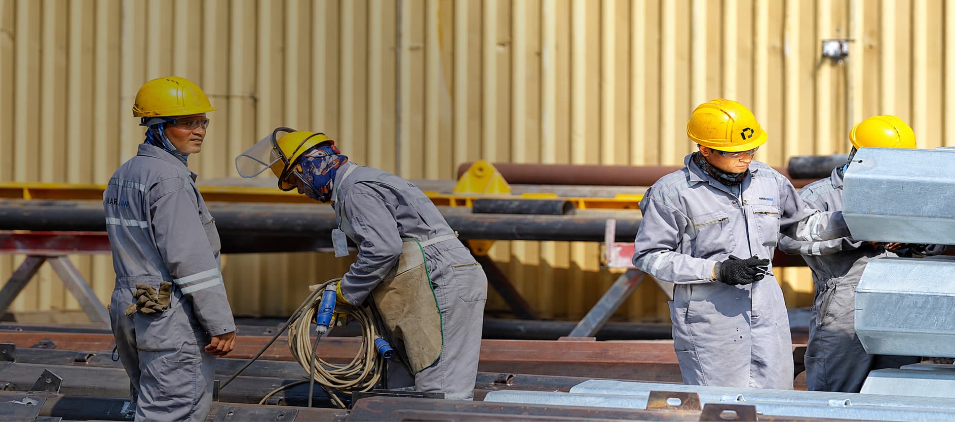 Site crew in safety gear working on fabricated steel sections