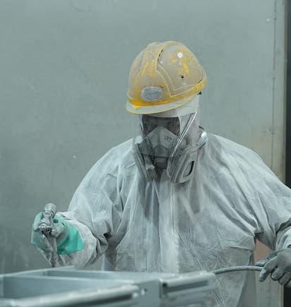 A painter in protective gear spray-coating a steel section
