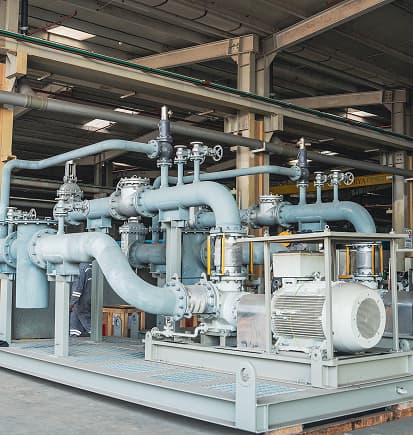 A pump skid with piping and valves on the workshop floor