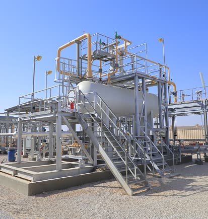 A steel support structure with stairs carrying a vessel and piping