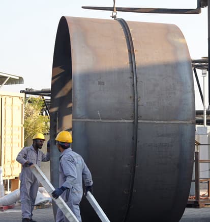 Prime Star workers guiding a lifted steel shell in the yard